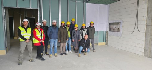 Il gruppo di amministratori e tecnici in visita al cantiere della scuola e gli interni della struttura.