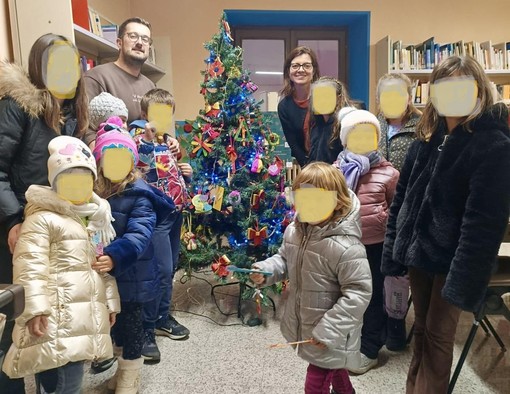 Il sindaco di Rifreddo Elia Giordanino con Erika Mustazzo e i bambini che hanno realizzato l'albero di Natale della biblioteca comunale