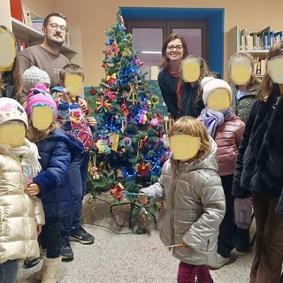 Il sindaco di Rifreddo Elia Giordanino con Erika Mustazzo e i bambini che hanno realizzato l'albero di Natale della biblioteca comunale