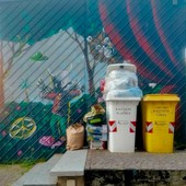 Bidoni e sacchi di immondizia davanti al murale di Moya in piazza Boves