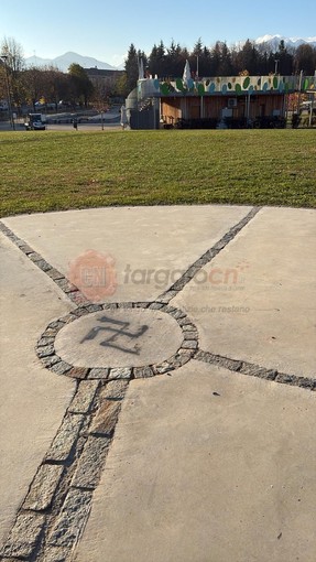 Una svastica disegnata a terra, in cima alla collinetta del parco